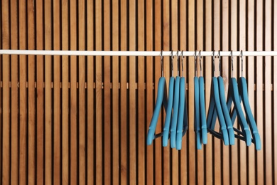 Photo of Empty hangers on rail against wooden background, space for text