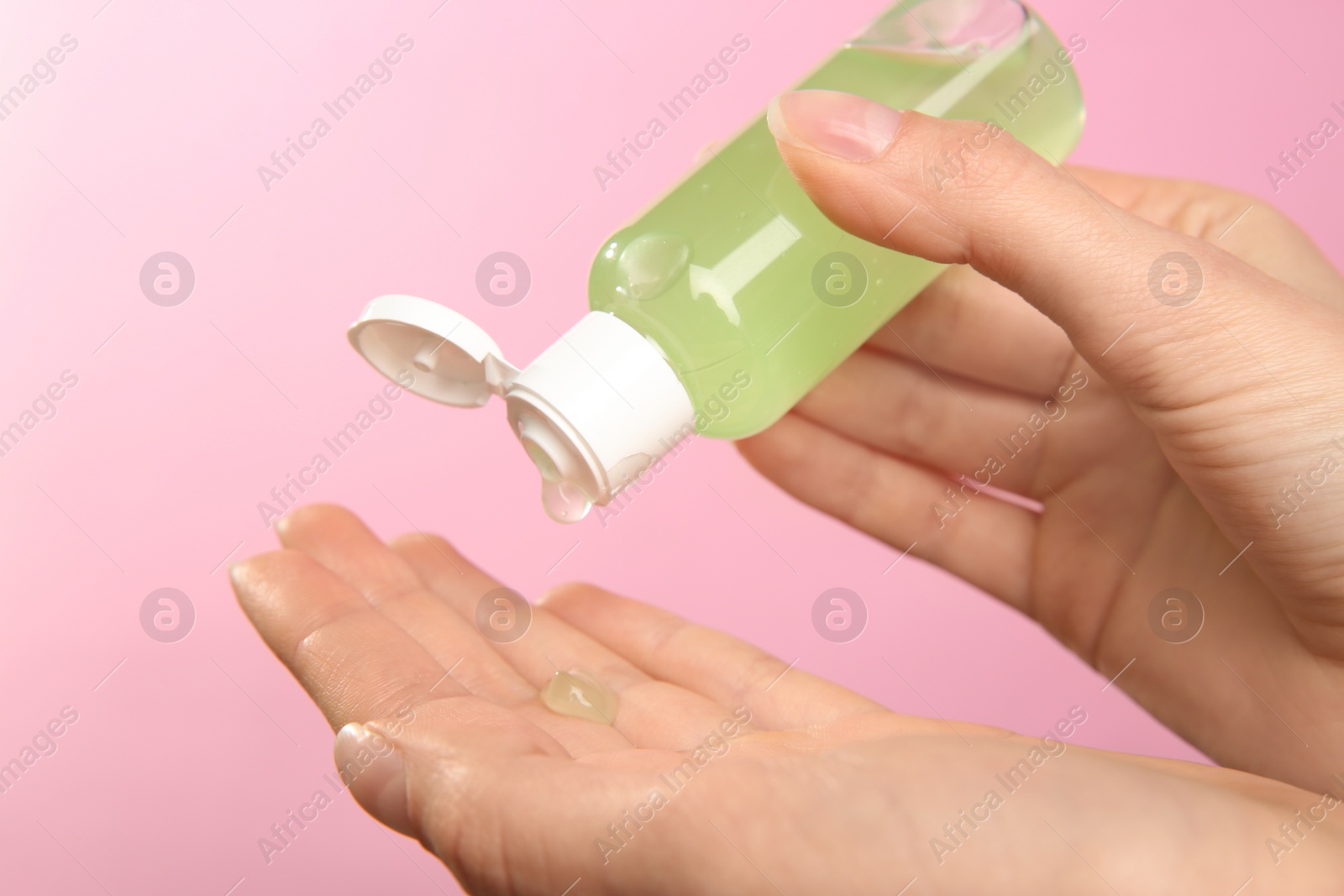 Photo of Woman applying antiseptic gel on pink background, closeup