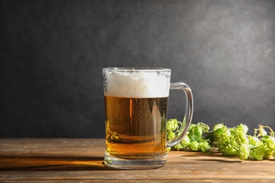 Composition with tasty beer and fresh green hops on wooden table