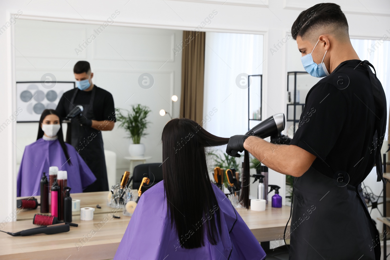 Photo of Professional stylist working with client in salon. Hairdressing services during Coronavirus quarantine