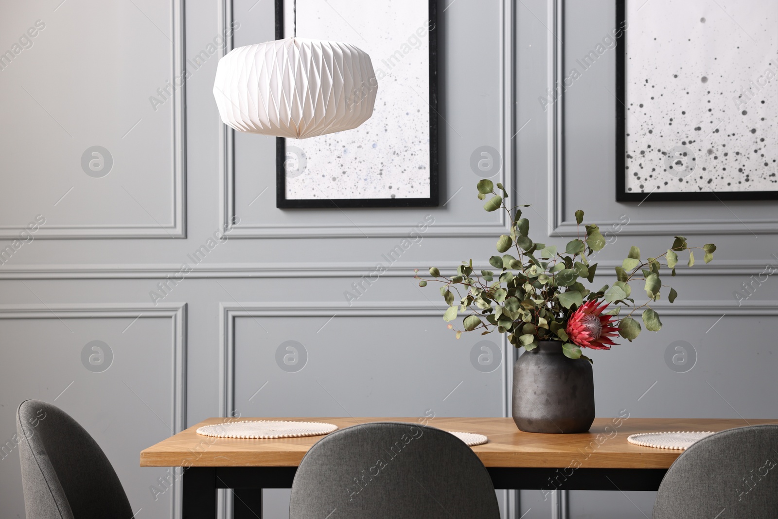 Photo of Soft chairs, table and vase with plants in stylish dining room