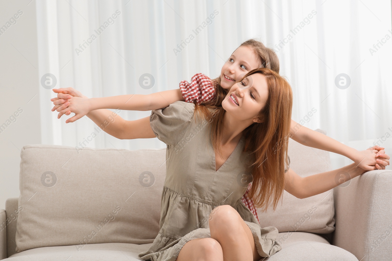 Photo of Mother with her cute daughter spending time together on sofa at home