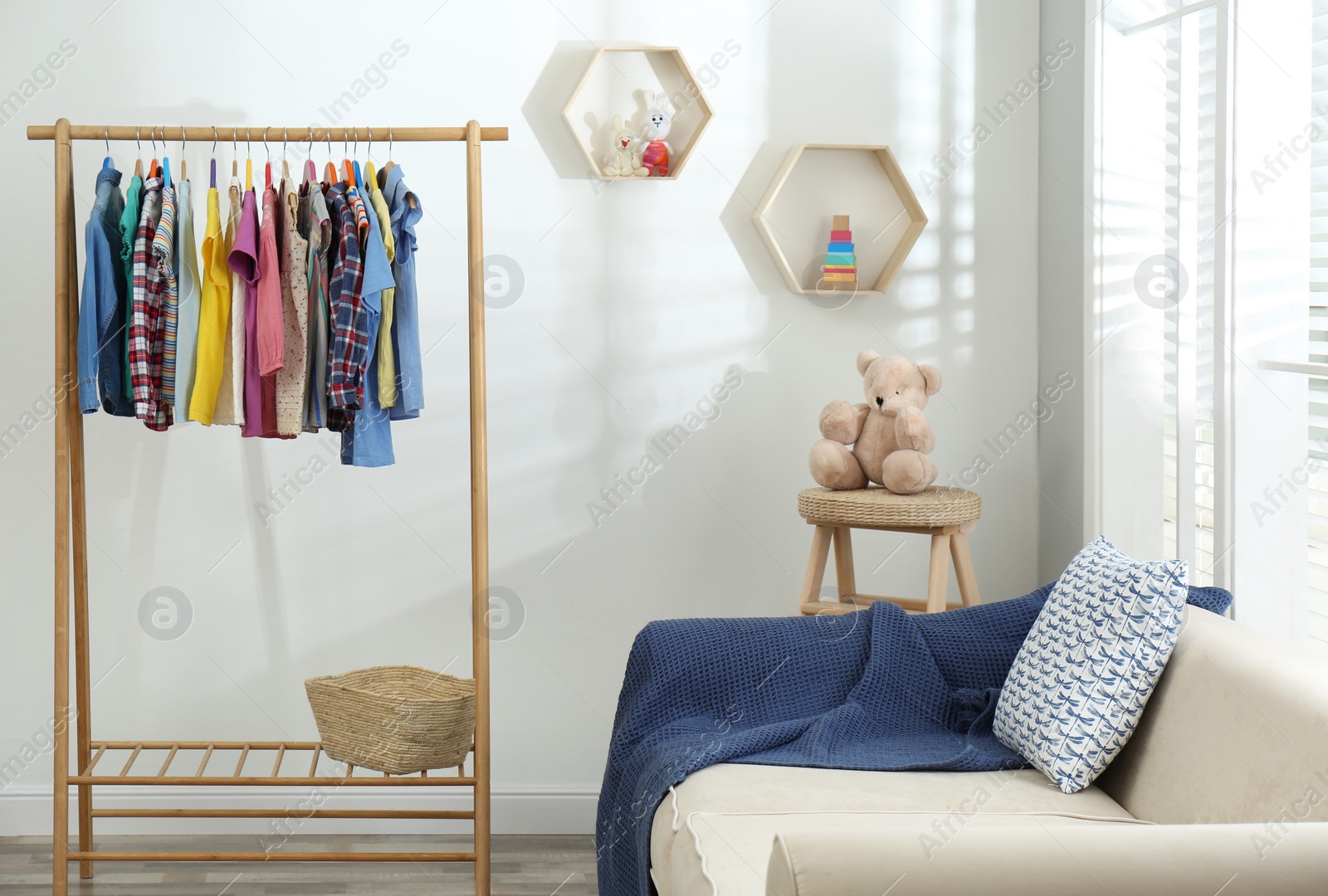 Photo of Different child's clothes hanging on rack in living room