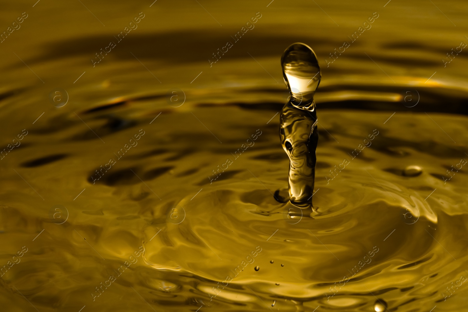 Image of Splash of golden oily liquid as background, closeup. Space for text