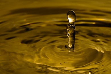 Image of Splash of golden oily liquid as background, closeup. Space for text
