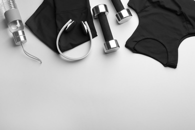 Flat lay composition with sportswear and equipment on light grey background, space for text. Gym workout