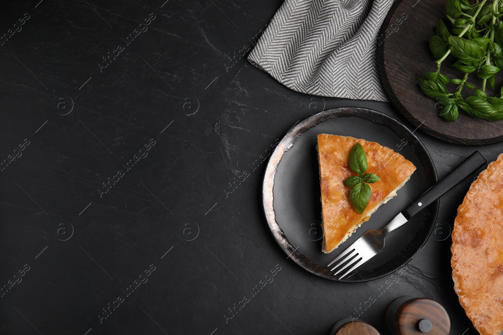 Photo of Piece of delicious pie with meat and basil on black table, flat lay. Space for text