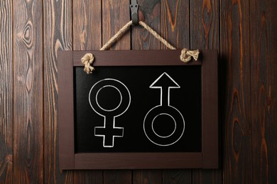 Image of Sex education. Small black chalkboard with female and male gender signs on wooden wall