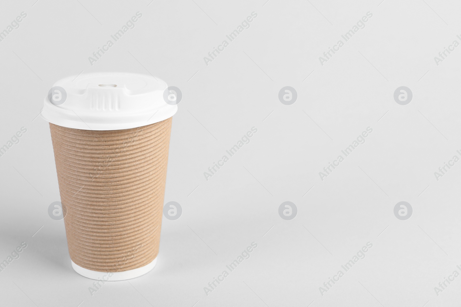 Photo of Paper cup with plastic lid on light background, space for text. Coffee to go