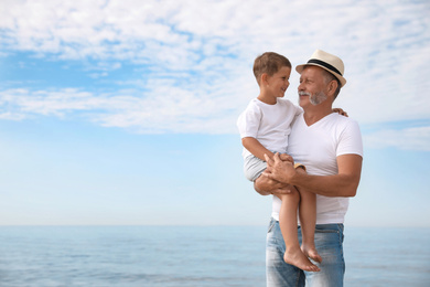 Photo of Grandfather with little boy near sea in summer