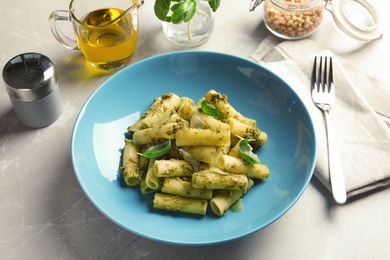 Photo of Plate with delicious basil pesto pasta on gray table