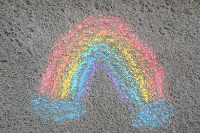 Photo of Rainbow drawn with colorful chalks on asphalt outdoors, top view