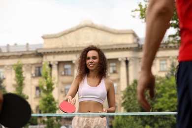 Photo of African-American woman playing ping pong with friend outdoors