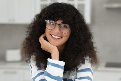 Photo of Portrait of beautiful woman with curly hair in kitchen. Attractive lady smiling and looking into camera