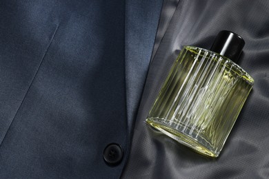 Photo of Luxury men's perfume in bottle on grey jacket, top view. Space for text