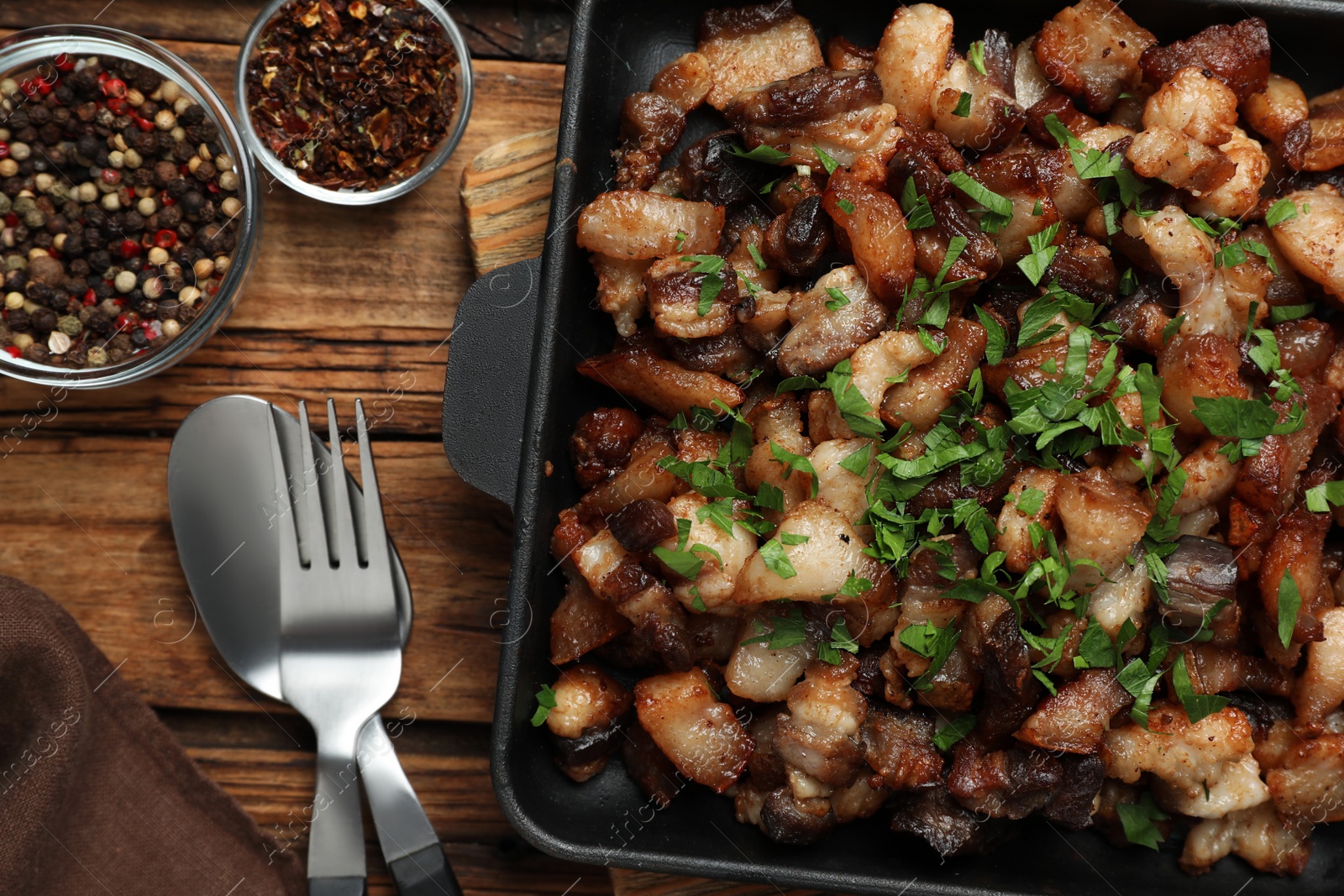 Photo of Tasty fried cracklings on wooden table, flat lay. Cooked pork lard