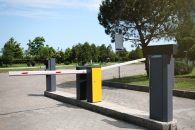 Photo of Modern road barriers and parking meter outdoors on sunny day