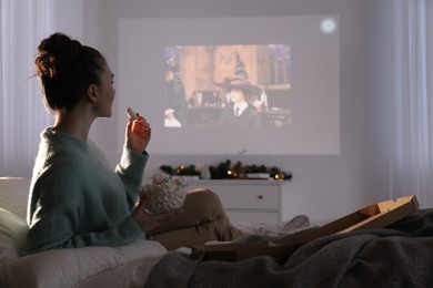 Lviv, Ukraine – January 24, 2023: Woman with marshmallows watching Harry Potter And The Philosopher’s Stone movie via video projector at home