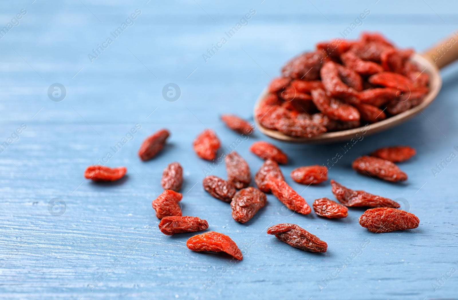 Photo of Dried goji berries on blue wooden table, closeup