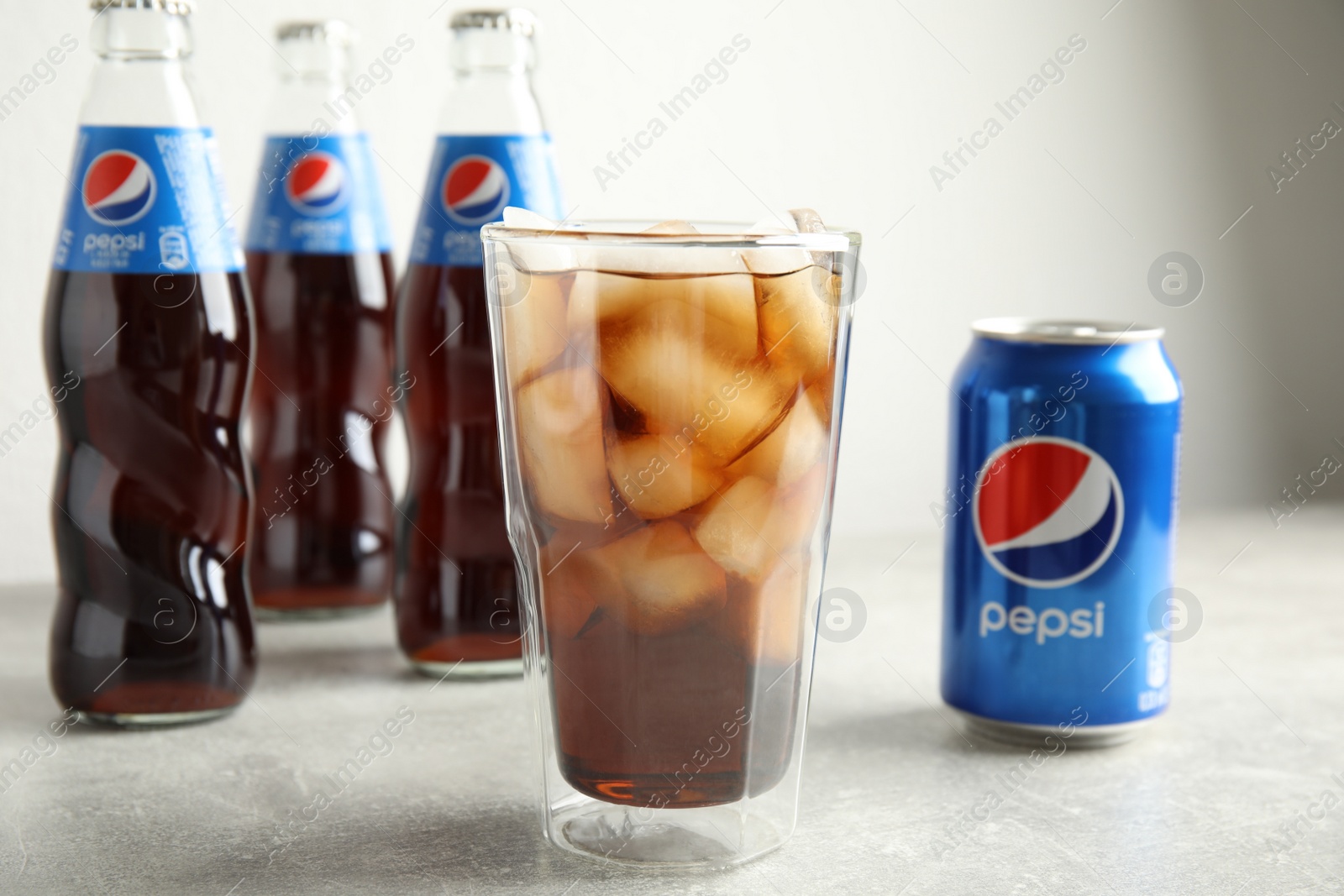 Photo of MYKOLAIV, UKRAINE - FEBRUARY 10, 2021: Glass, can and bottles of Pepsi on grey table