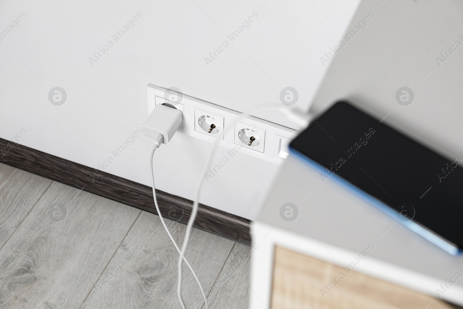 Photo of Modern smartphone charging from electric socket indoors