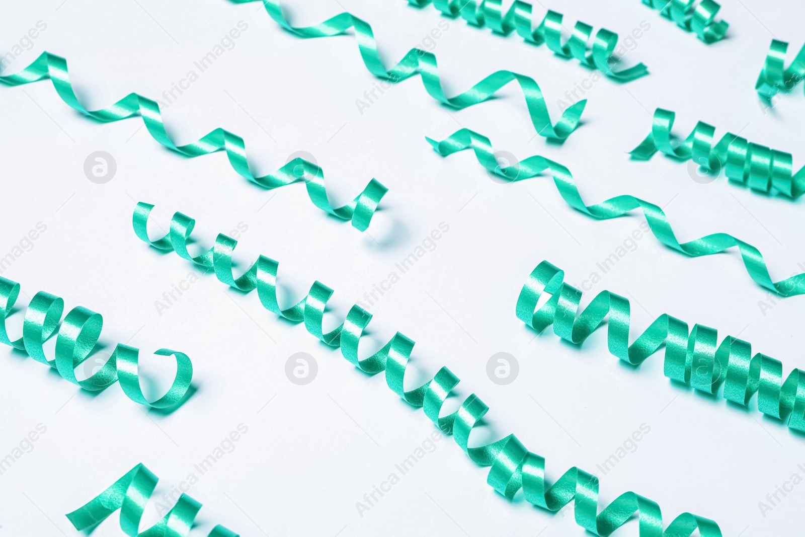 Photo of Many turquoise serpentine streamers on white background