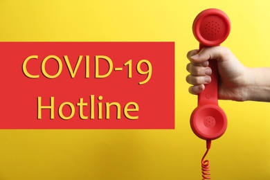 Image of Covid-19 Hotline. Woman with red handset and text on yellow background, closeup
