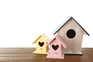 Photo of Three different bird houses on wooden table against white background