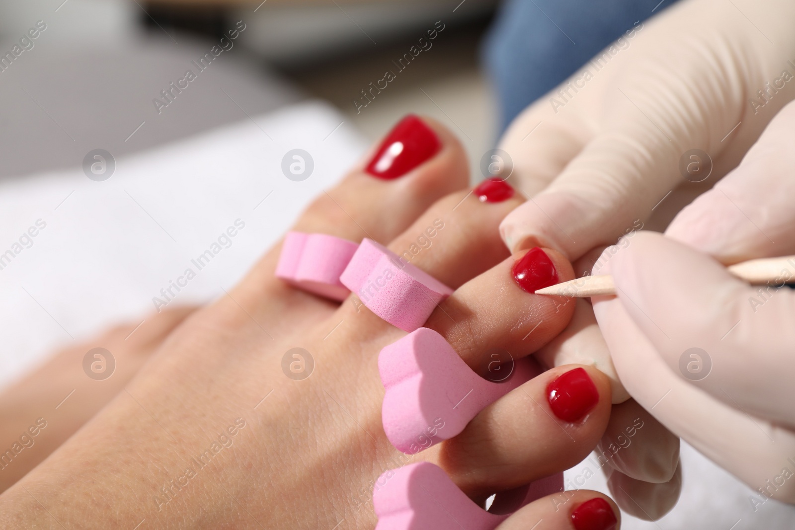 Photo of Pedicurist working with client`s toenails in beauty salon, closeup