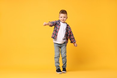 Photo of Happy little boy dancing on yellow background. Space for text