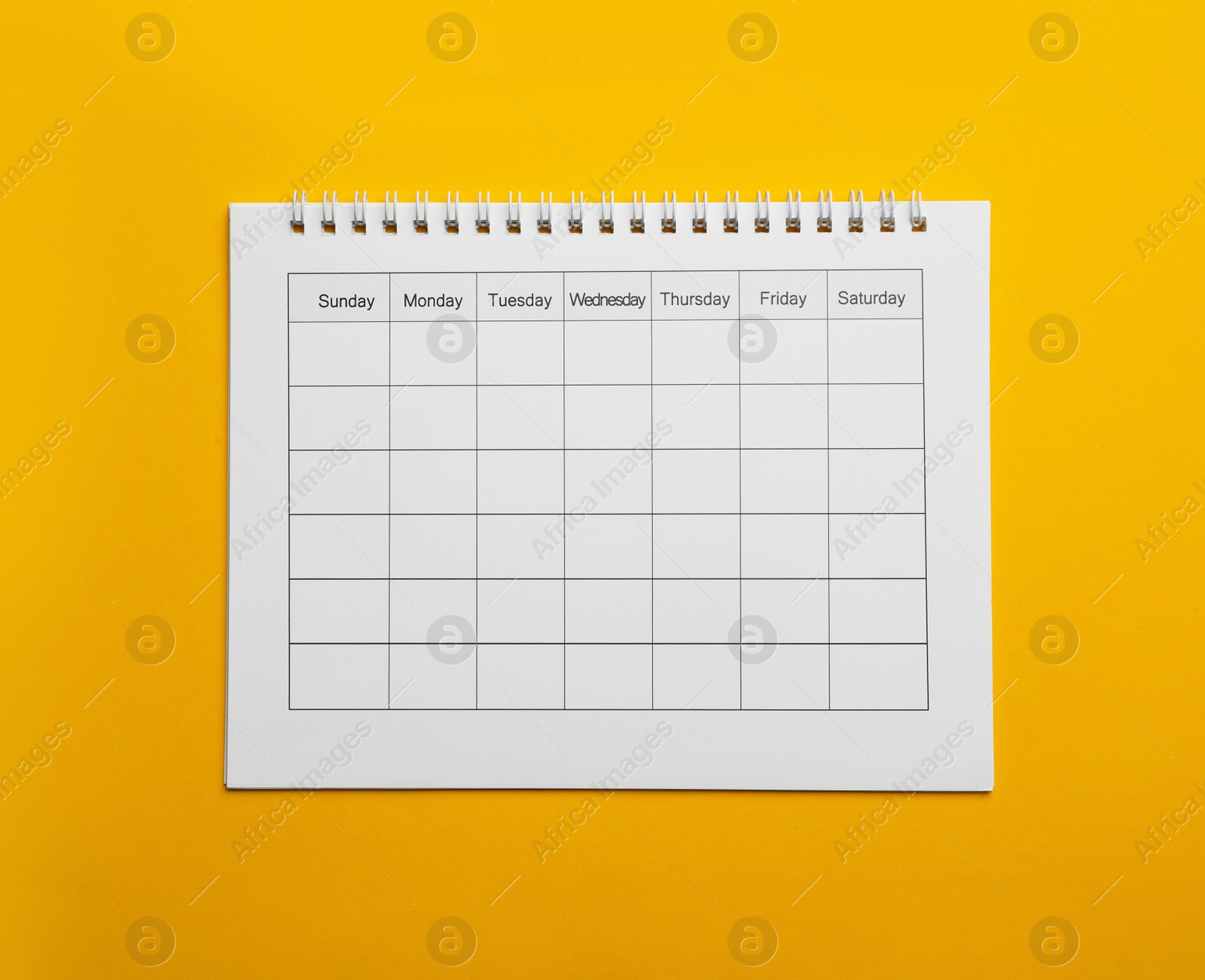 Photo of Blank calendar on yellow background, top view