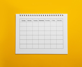 Photo of Blank calendar on yellow background, top view