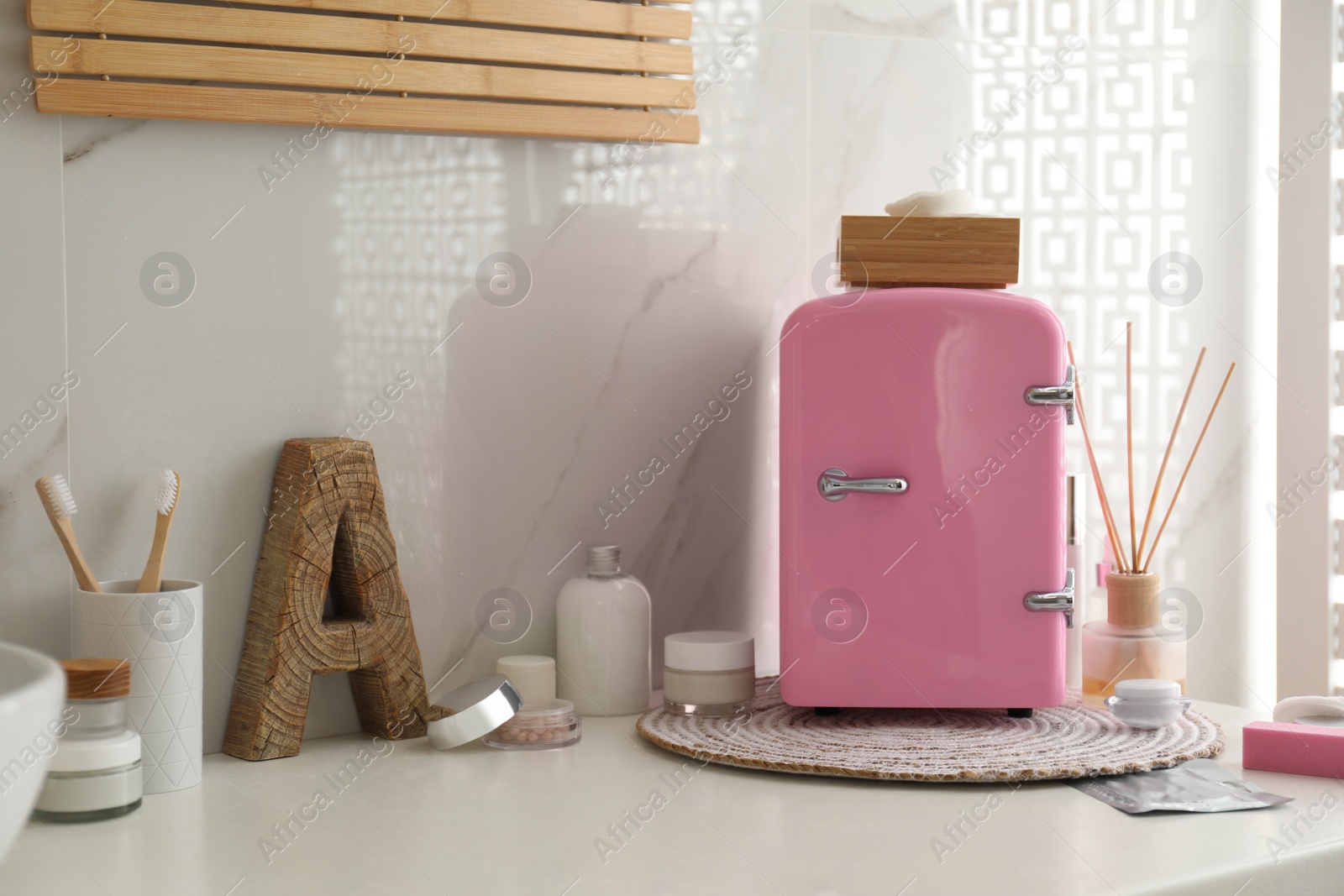 Photo of Cosmetics refrigerator and skin care products on white table indoors