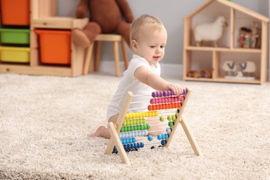 Children toys. Cute little boy playing with wooden abacus on rug at home