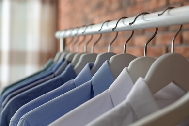 Wardrobe rack with men's clothes on hangers, closeup