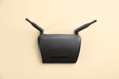 Modern Wi-Fi router on beige background, top view