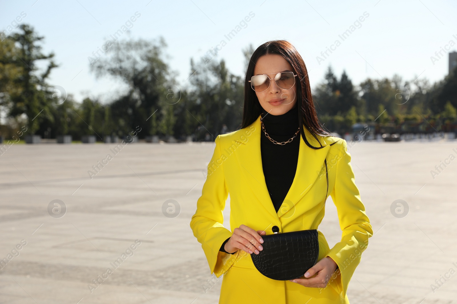 Photo of Beautiful young woman with stylish waist bag on city street, space for text