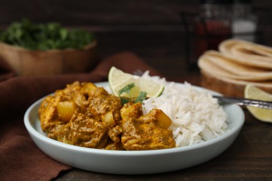 Photo of Delicious chicken curry with rice on wooden table, closeup