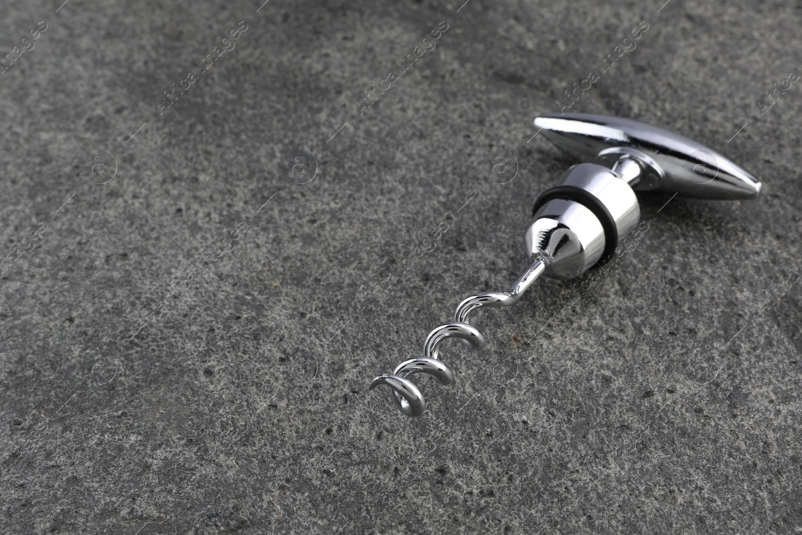Photo of One metal corkscrew on grey textured table. Space for text