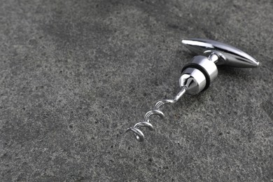 One metal corkscrew on grey textured table. Space for text