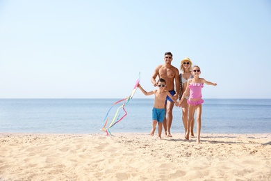 Photo of Happy family with kite at beach on sunny day