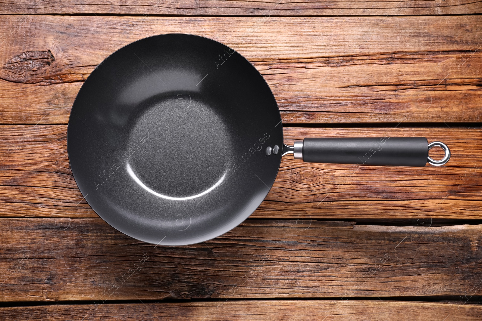 Photo of Empty iron wok on wooden table, top view. Chinese cookware