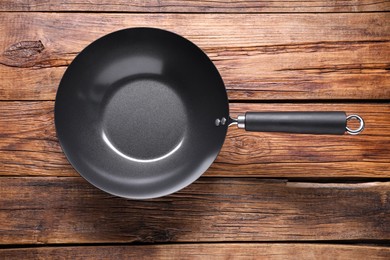 Photo of Empty iron wok on wooden table, top view. Chinese cookware