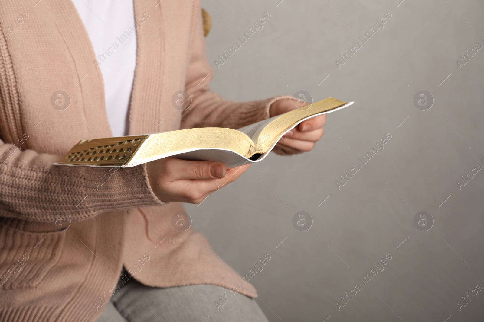 Photo of Woman reading Bible against light background, closeup