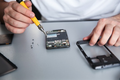 Photo of Technician repairing mobile phone at table, closeup