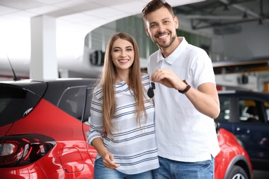 Photo of Happy woman and man with car keys in modern auto dealership