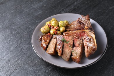 Delicious fried beef meat, vegetables and thyme on black table