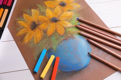 Photo of Colorful chalk pastels, pencils and beautiful painting of flowers on white wooden table, above view