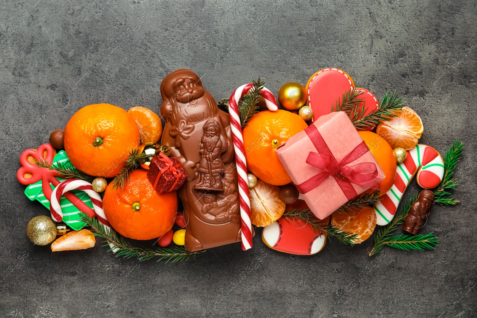 Photo of Flat lay composition with chocolate Santa Claus candies on grey table