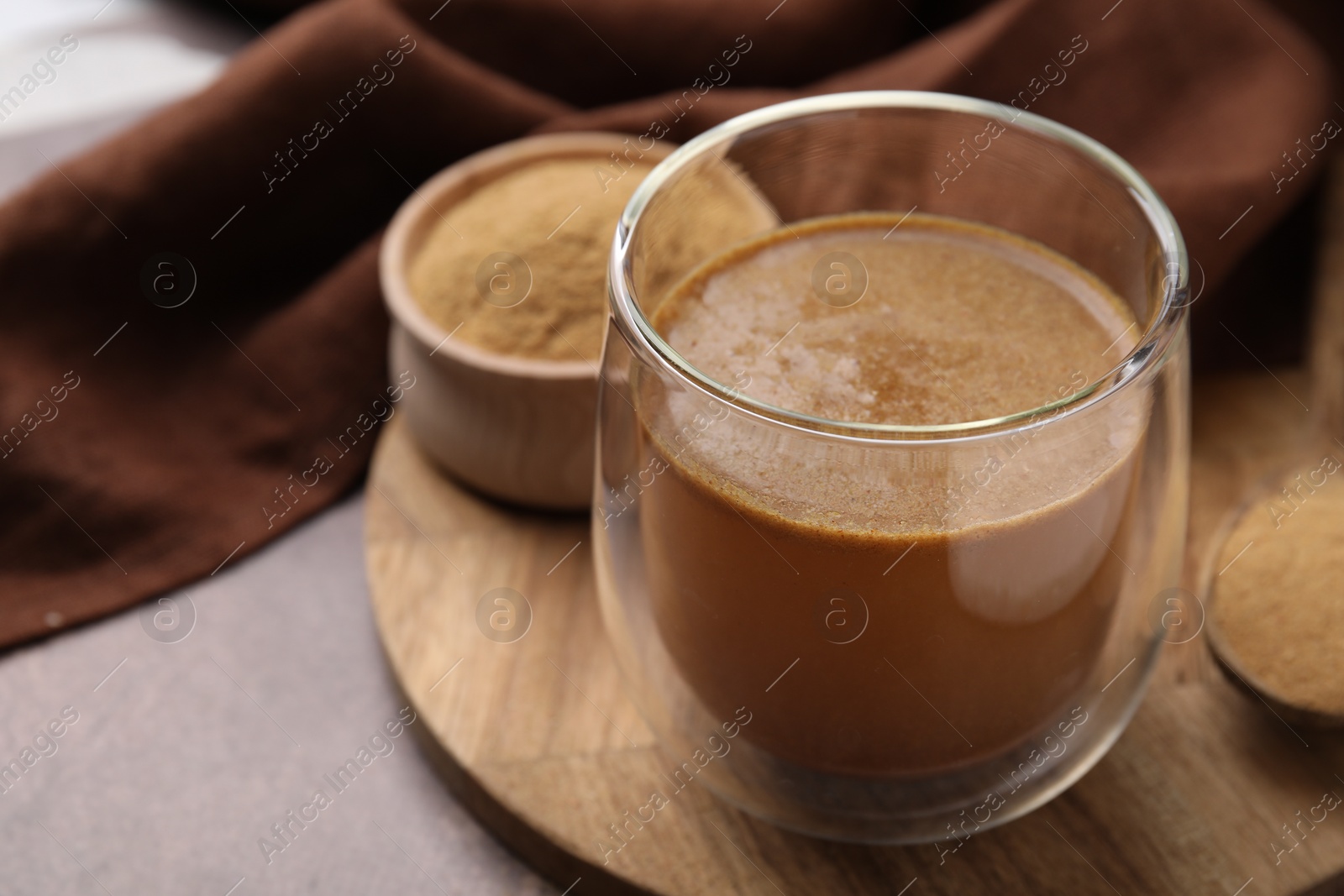 Photo of Soluble fiber with water in glass and powder on brown table, closeup